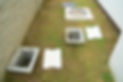 Concrete inspection pits and covers are laid out on grass beside a building