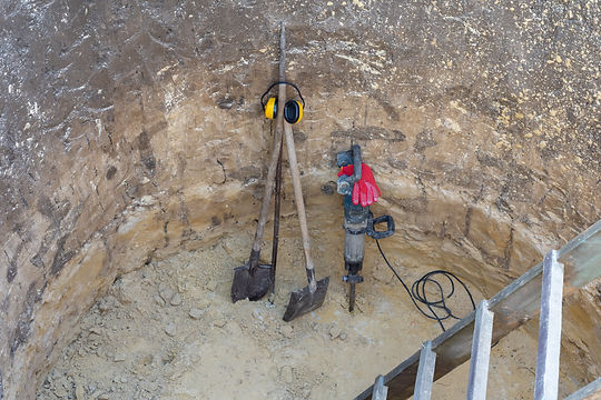Professional jackhammer, shovel, crowbar, ladder and protective equipments in deep pit.