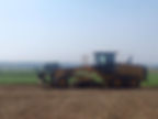 A tractor plows a sunlit field, showcasing agricultural activity during the day