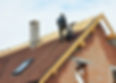 Roofing contractors installing shingles on a residential house construction site