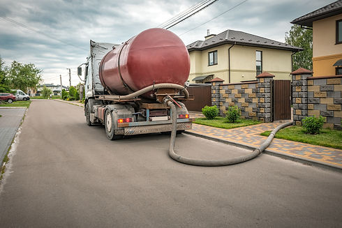 Septic truck with a large red tank parked on a residential street
