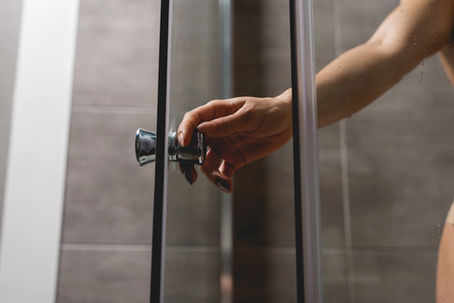 Selective focus on a hand opening a glass shower door