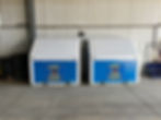 Two blue and white refrigerators positioned side by side in a spacious warehouse setting.