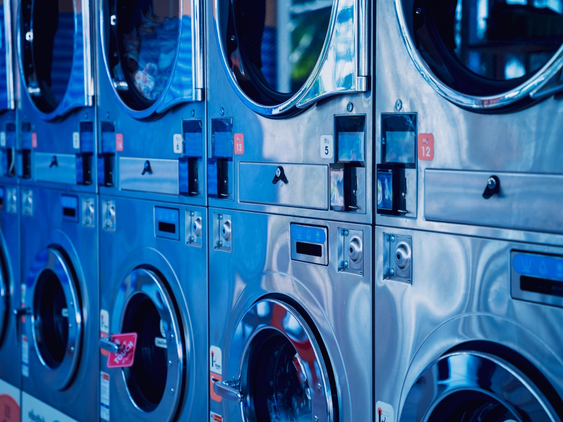 Row of commercial washers and dryers in a professional laundry facility.