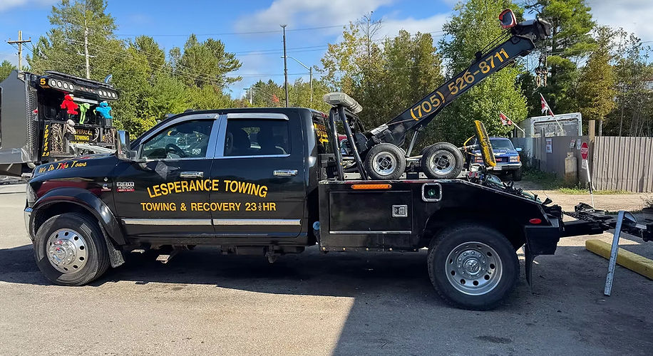 Black recovery tow truck lifting damaged vehicle equipment carefully