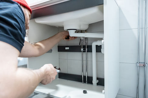 Plumber installing a new faucet under a bathroom sink