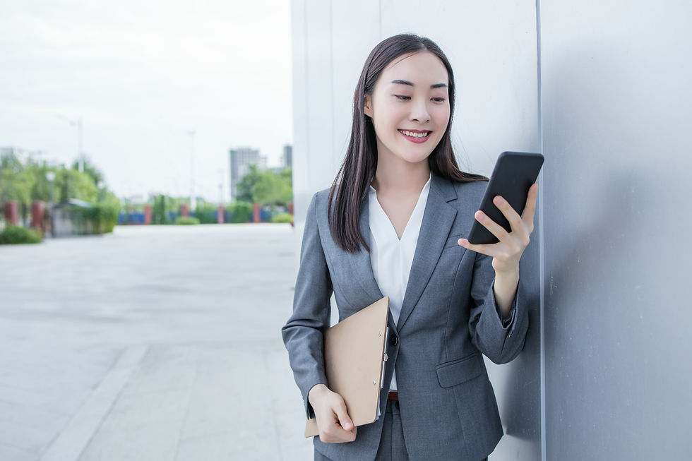 A woman smiling as she looks at her phone.