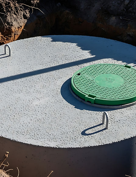 Fosse septique en béton avec couvercle circulaire vert partiellement enterrée dans le sol