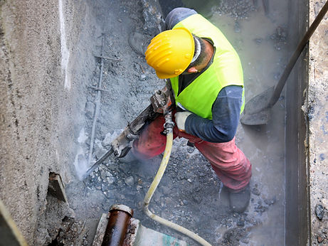 Worker demolish old concrete wall with jackhammer