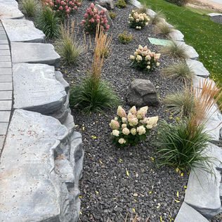 A stone retaining wall frames a patio area
