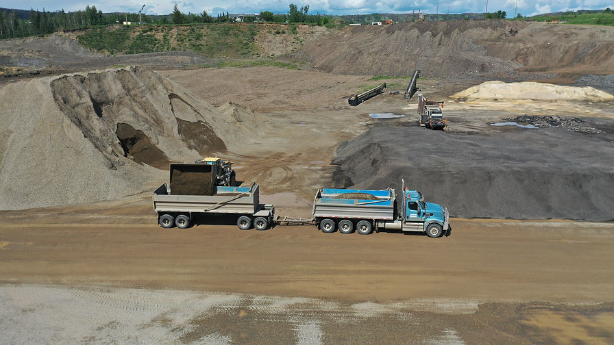 Dump trucks operating at an aggregate pit, providing sand and gravel supply for construction