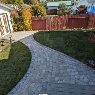 A serene backyard featuring a cozy patio and a charming brick walkway