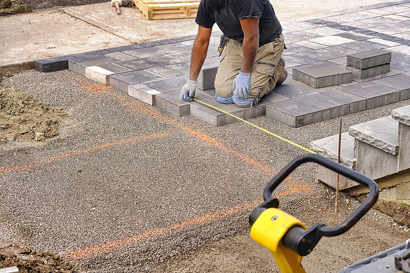 Landscaping contractor worker using tape measure ruler measuring and laying interlock ston