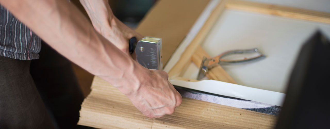 hands stretching the canvas on the stretcher