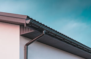Close-up of a house's modern black gutter system against a clear blue sky
