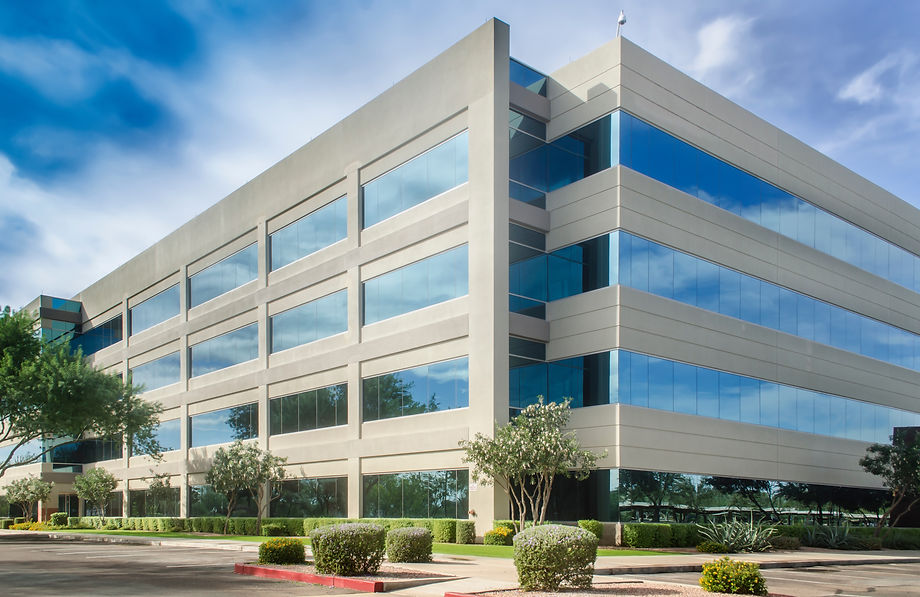 Building adorned with numerous windows, surrounded by abundant greenery.