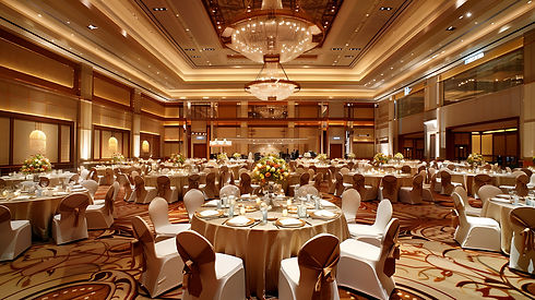 Grand ballroom interior showcasing elegant table settings with white tablecloths and brown chairs