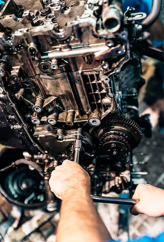 A mechanic works on a disassembled engine