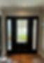 Black front door with stained-glass side panels in a well-lit entryway.