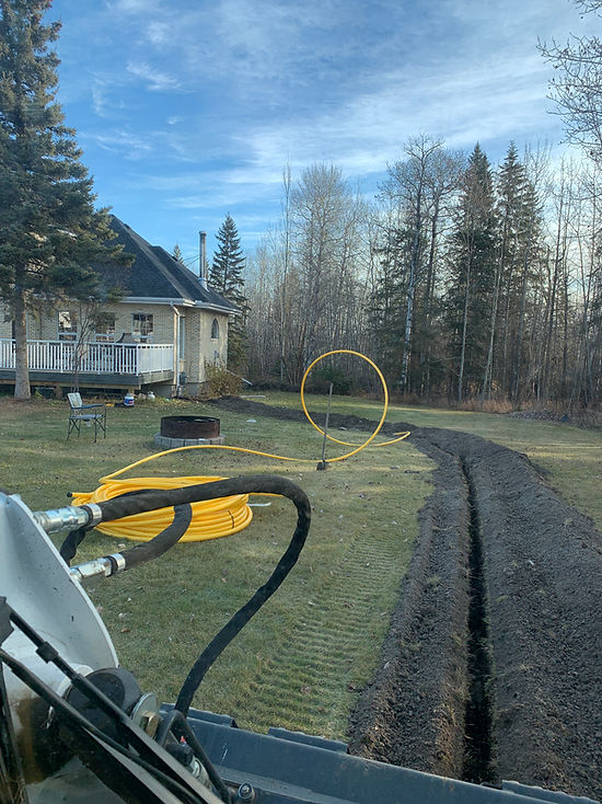 Trench excavation beside a residential property with heavy equipment