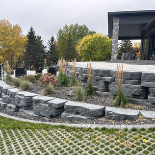 A stone retaining wall supports a patio
