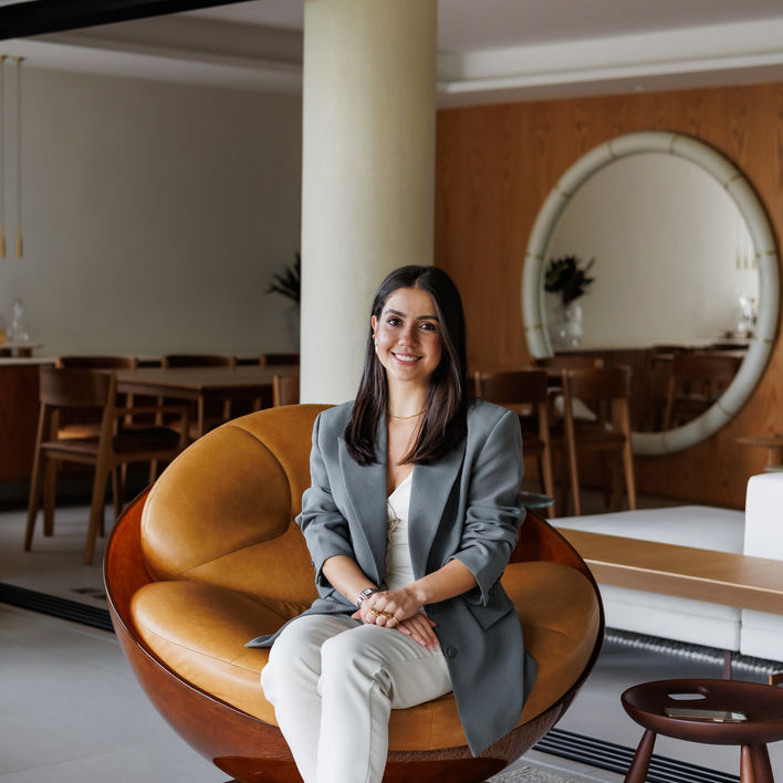 Mulher sorrindo sentada em uma cadeira, Apartamento DOM - Leblon, RJ, em ambiente moderno.