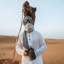 Man posing with a camel in the desert near Jaisalmer, India, bordering a nearby town in Pakistan.