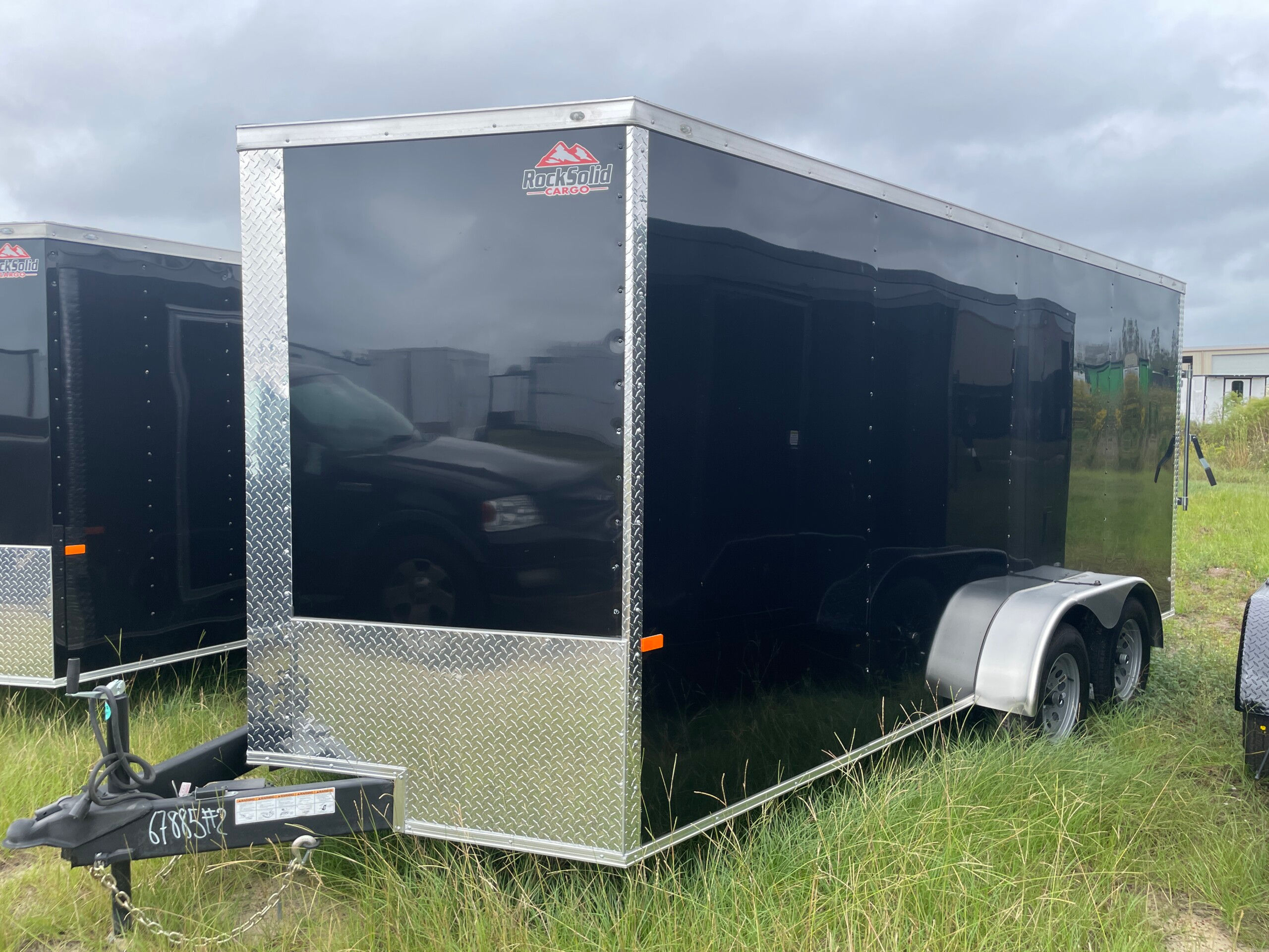 Black 7x16 tandem axle enclosed cargo trailer with .080 Polycore exterior, semi-screwless construction, V-nose design, and ramp door