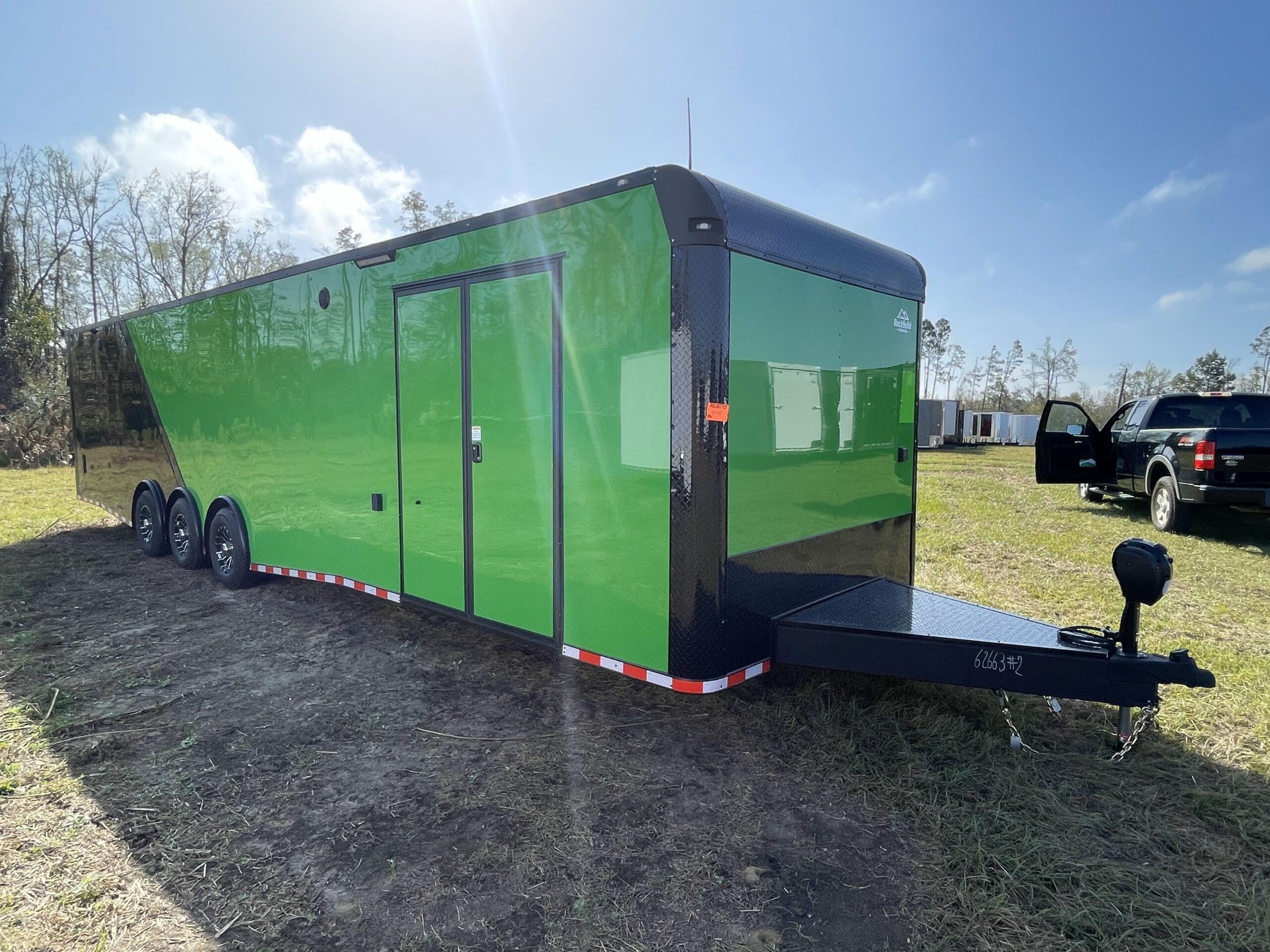 Rock Solid Cargo 8.5x36 enclosed race car trailer with Lucky Green and black polycore exterior, triple torsion axles, escape door, electric awning, cabinets, and E-track flooring for sale.