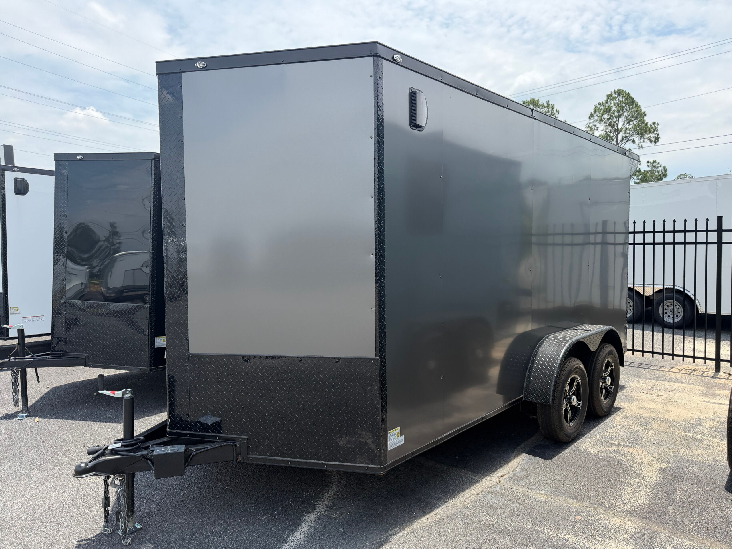 Deep South 7x14 tandem axle enclosed cargo trailer in charcoal gray with blackout package, 7-foot interior height, Polycore semi-screwless exterior, rear spoiler with LED light, alloy wheels, ramp door, and side entry door.