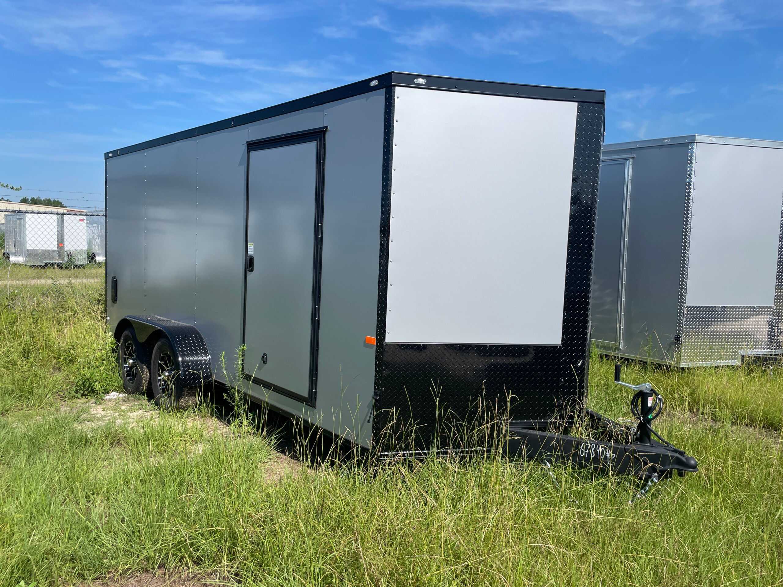 7x16 tandem axle enclosed cargo trailer with .080 Polycore exterior, blackout package, alloy wheels, V-nose design, and ramp door