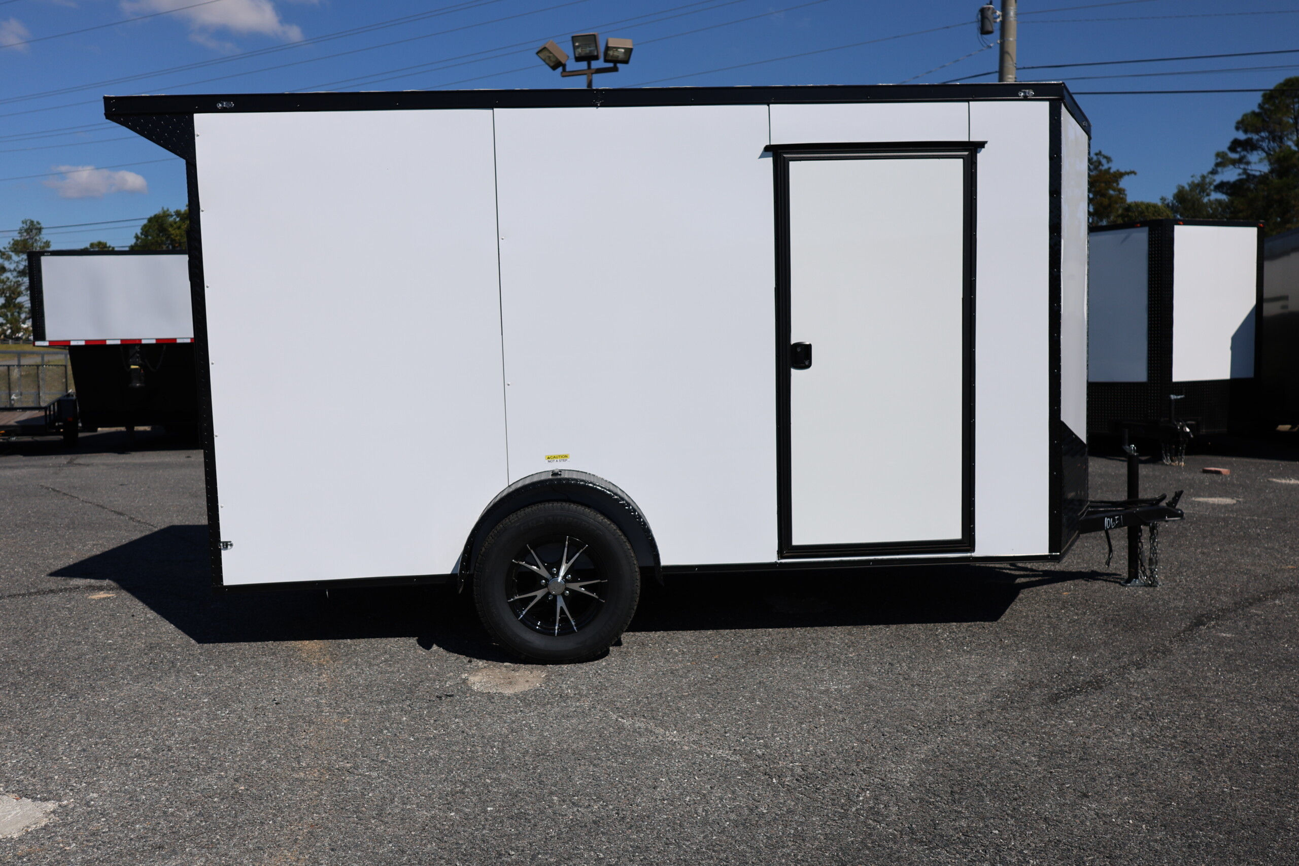 Deep South 6x12 enclosed trailer with white Polycore exterior, blackout package, alloy wheels, spoiler, and ramp door.