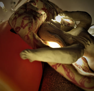 A clay model of a person lays on a washbag, balanced on a selection of bathroom items.
