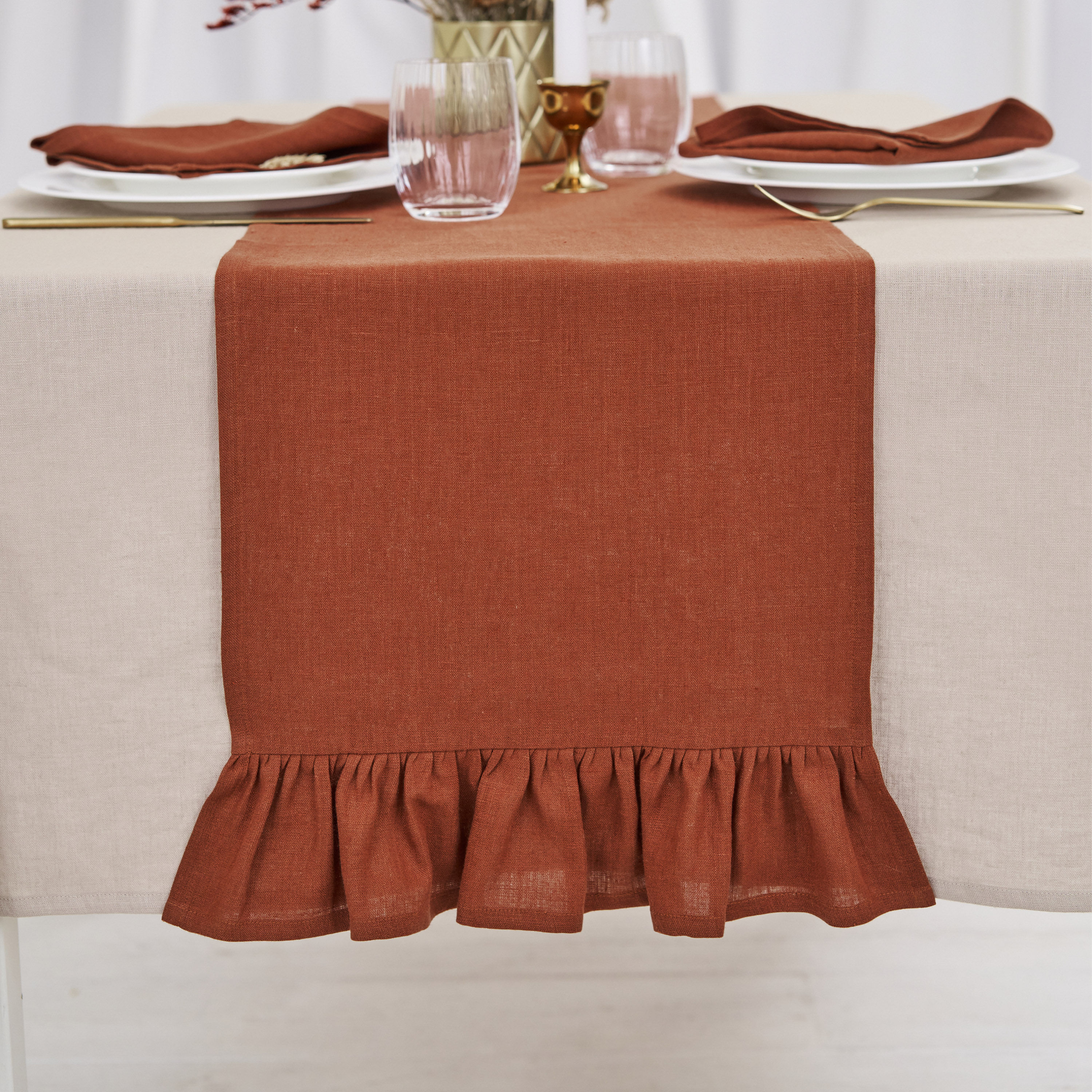 Burnt orange linen table runner with ruffles on a minimalist dining table