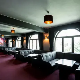 Lounge cu canapele din piele neagra, mese joase si ferestre arcuite la Rasnov