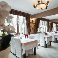 Sala de restaurant cu mese aranjate, scaune albe si candelabre la International Rasnov