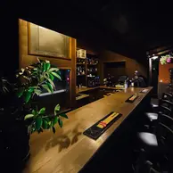 Bar lung din lemn cu scaune si plante verzi intr-un interior seara la Rasnov
