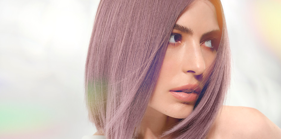 Image of a person with lavender colored, shoulder length hair that is parted down the middle and styled straight.