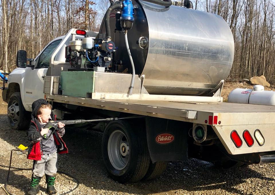 Crew cleaning small septic truck.