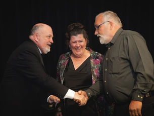 Fernmania representative shaking hands on stage after receiving the Environmental Excellence award at the 2026 CareSuper Business Excellence Awards.