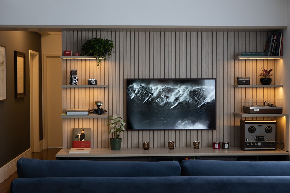 Estante multimídia para coleções de equipamentos de som e imagem. Painel de marcenaria para TV. TV que exibe quadros e fotografias.