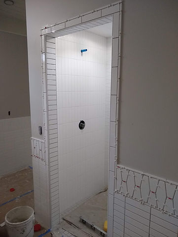 Curbless entry way into grotto style shower. Entry doorway framed with stretched subway tile, walls all subway tile up to chair rail height with stretched hexagon ceramic tile, cut in half and flipped then capped with pencil liner