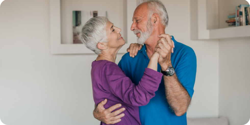An older couple dancing in their living room.