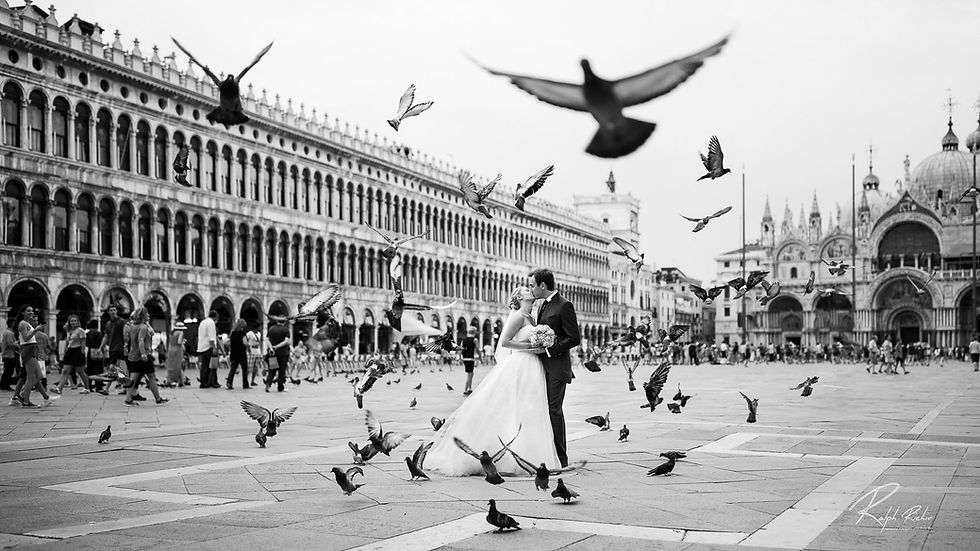 Mariés qui s'embrassent place Saint-Marc à Venise dans un envol de pigeons, photo de mariage en noir et blanc de Ralph Richir
