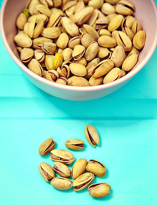 pistachos-en-tazon-rosa-sobre-fondo-de-mesa-de-madera-azul (1).jpg