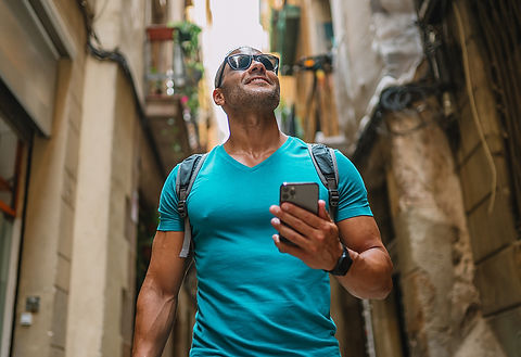 Confident man using his phone for directions as he walks along a street in Italy Photograp