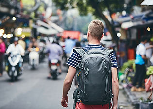 A young male traveller with a backpack explores a street market