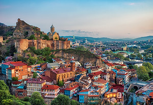 Tbilisi spills down its hillsides into the Mtkvari River, a jumble of wooden balconies, wi