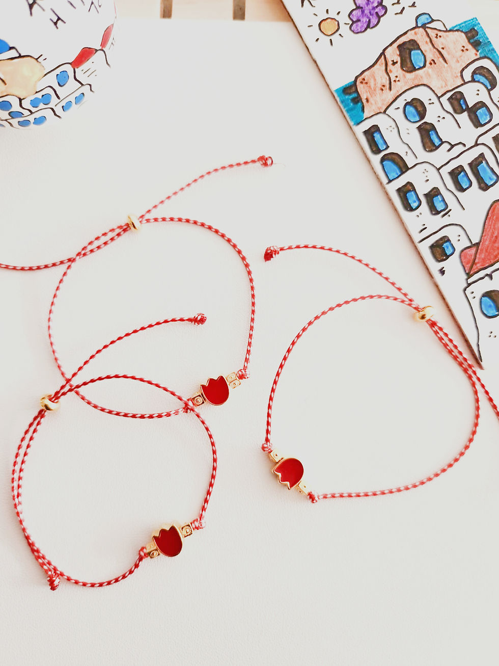 Three red string bracelets with tulip charms