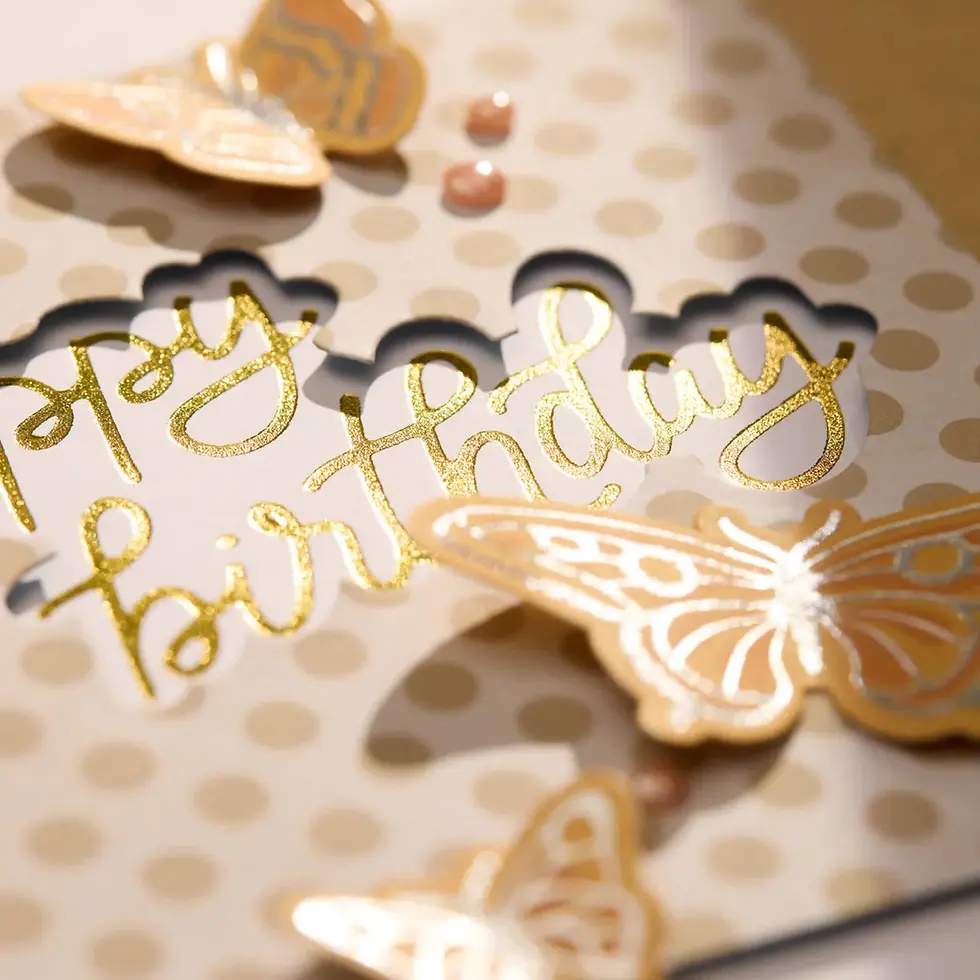 Carte d’anniversaire à pois or avec papillons dorés et texte happy birthday en lettres scintillantes.